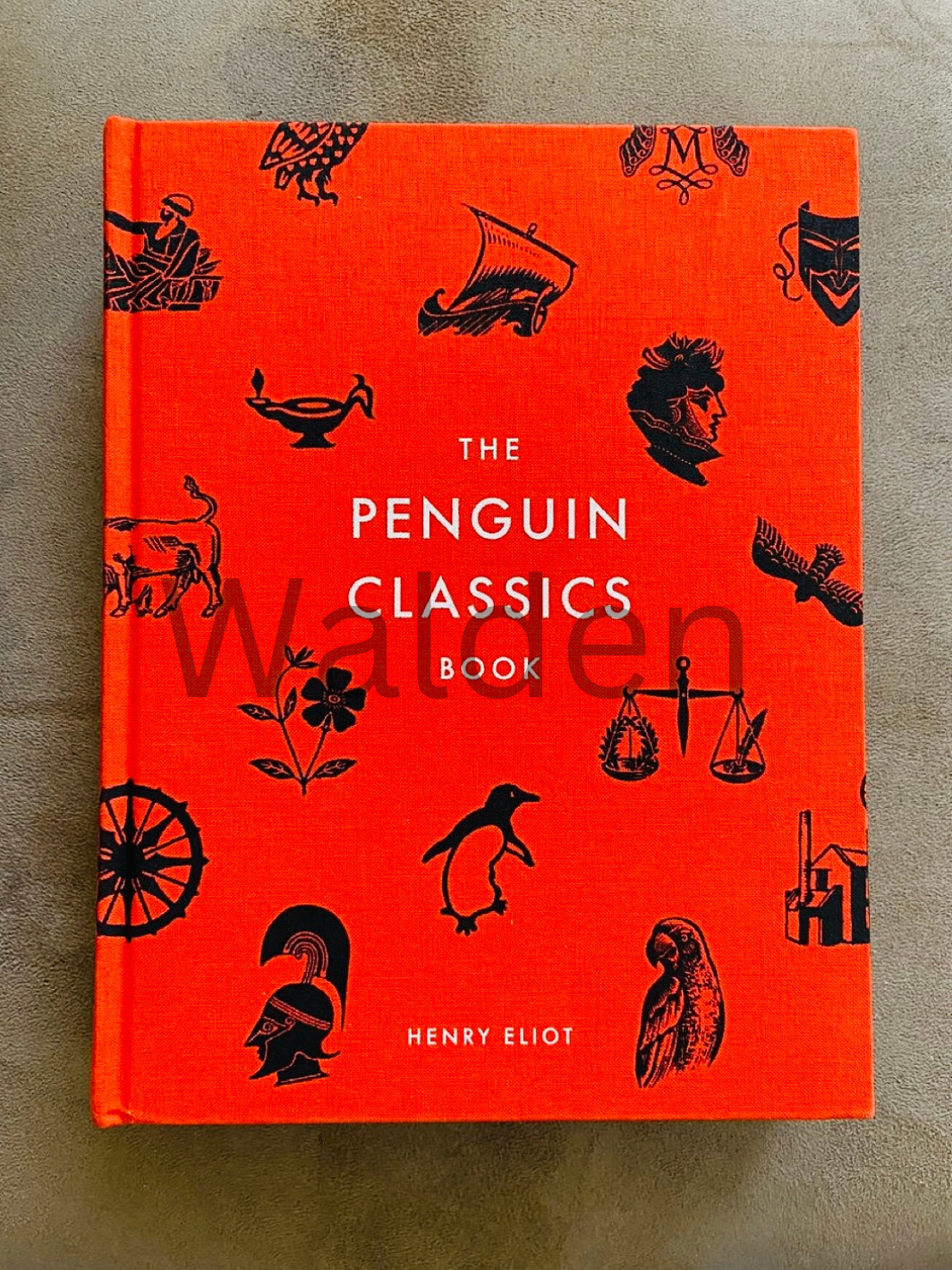 Book cover design for “The Penguin Classics Book” — black classical motifs on a vivid orange clothbound cover